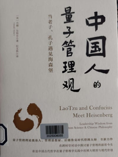 这是管理类书籍《中国人的量子管理观》的官方封面，封面以白色为底色，设计简约大气：上方是醒目的黑色书法字体主标题“中国人的量子管理观”，搭配副标题“当老子、孔子遇见海森堡”；左侧标注了作者[英]丹娜·左哈尔与译者纪文凯的信息；下方有棕色水墨风格图形，以及英文标题“LaoTzu and Confucius Meet Heisenberg”，还有书籍的定位语与内容介绍，表明该书将中国古代哲学与现代量子科学结合，探讨管理智慧。封面还带有图书馆的条形码标签“2025006055”。