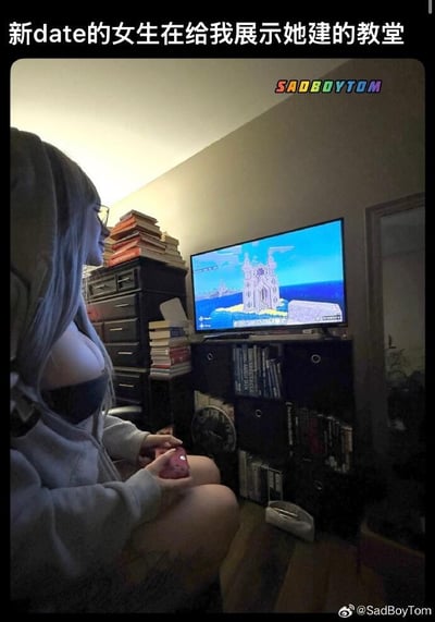 图中展示了一位戴着眼镜、有着灰色长发的女生，她穿着灰色连帽衫，正专注地用粉色游戏手柄操作着游戏。她面前的电视屏幕上显示着《我的世界》(Minecraft)游戏画面，画面中是一座她建造的精美教堂/城堡建筑。女生坐在房间里，身后有堆满书籍的抽屉柜和书架，整体场景呈现出年轻人的生活空间氛围。
