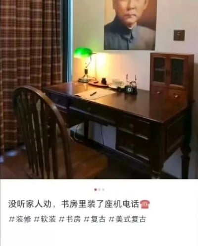一间复古风格的书房场景，房间内摆放着深色木质书桌，桌上有绿色灯罩台灯、老式旋转拨号座机电话、纸笔和茶杯。书桌旁有一把木质椅子，墙上挂着一幅人物肖像画，窗边挂着棕色格子窗帘。图片下方配有文字“没听家人劝，书房里装了座机电话”及相关装修类 hashtags，营造出一种怀旧又略带幽默的氛围。