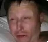 图片中显示一名男子躺在床上，面部表情呈现出明显的悲伤情绪，眼睛微闭，嘴巴张开，似乎正在哭泣。背景为简单的床铺，整体画面聚焦于人物的情绪状态，给人一种情绪崩溃或极度难过的感觉。