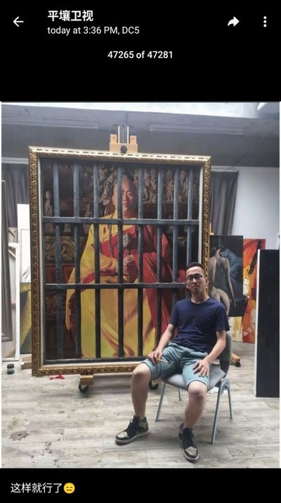 这张图片是一种错位创意摄影，拍摄者借助油画和椅子，营造出人物仿佛被关在监狱牢笼里的视觉效果。画作前有牢笼状栏杆，后面画着一位身穿黄色与红色服饰的人物。现场一名男子坐在画前方的椅子上，巧妙地使上半身和画中人物“合体”，通过位置融合产生“被关押”的幽默场景。底部配文“这样就行了😑”表达一种敷衍、无奈或调侃意味，带有轻松搞笑气氛。

此图没有明显双关、谐音梗，但利用视觉错位和语气符号传递出幽默感和网友常用的“敷衍式完成任务”情绪。