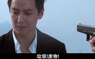 这张图是电影《新警察故事》的相关表情包素材，画面左侧是吴彦祖饰演的角色关祖（阿祖），他眉眼低垂，面露委屈难过的神态，画面右侧有一只手举着手枪对准他，图片底部配有白色加粗文字“垃圾！废物！”，整体传递出训斥、否定的情绪。