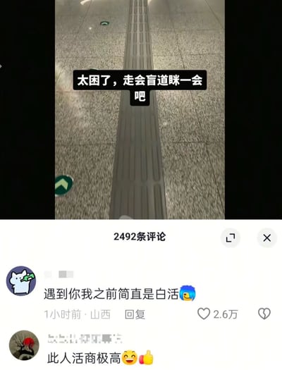 图片展示了一段地面盲道的特写，中间有一条长长的灰色盲道带，两侧是浅色的大理石地面。画面上方有黑色背景白色文字的叠加："太困了，走会盲道眯一会吧"。图片下方显示了社交媒体评论区，有两条高赞评论："遇到你我之前简直是白活"和"此人活商极高"，分别获得了2.6万点赞。

图片通过双关语制造幽默效果，将盲道的功能曲解为可以让人闭着眼睛行走的"安全通道"，从而实现"眯一会"的目的，形成了一种荒诞又搞笑的反差感。