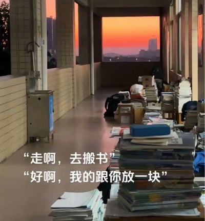 整张图拍摄的是中学教学楼的走廊场景，黄昏时段橙红色的日落景观透过走廊尽头的窗口呈现，走廊右侧摆放的课桌上堆叠着大量学生的书本、资料，还有书包等个人物品，左侧墙边设有公用直饮水机，整体氛围静谧又充满校园气息。图左下角配有两句对话文字，还原了学生时代的常见对话，容易引发有中学就读经历的人群的怀旧共鸣。