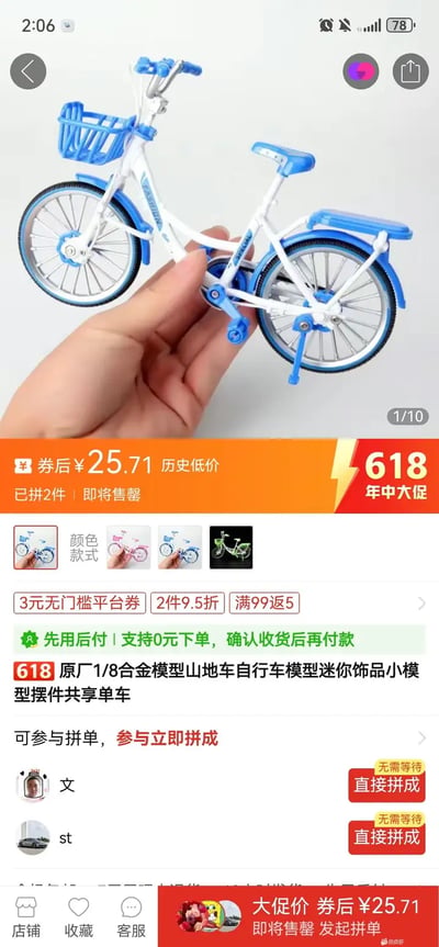 这是一张截取自电商平台商品页的图片，展示了一个1/8比例的迷你自行车模型，仿照真实的共享单车风格设计，配色以蓝白为主。图片上有明显的促销信息，突出“618年中大促”活动和历史最低价，同时带有拼单分享和优惠券等促销细节。手托自行车模型，用于突出商品体积较小。整张图风格偏向搞笑，因为这样一个“迷你共享单车”实际只能作为模型、摆件或玩具，和现实生活中的共享单车形成了强烈对比，有一定的反差幽默感。没有谐音梗、暗示等成分，纯商品促销风格。