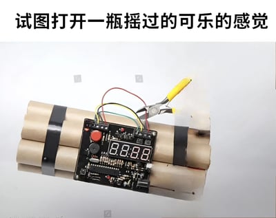 图片展示了一个由纸筒和电子元件组成的自制炸弹装置，上面有一个显示'88:88'的数字显示屏和一把钳子。图片上方配有文字'试图打开一瓶摇过的可乐的感觉'，通过夸张的比喻，将打开摇晃过的可乐时的紧张感幽默地比作拆弹的场景。
