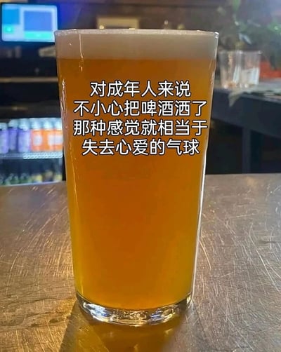 这是一张文字加注的实拍静态图，画面主体是一杯盛满橙黄色精酿啤酒的玻璃杯，放置在带有划痕的深色吧台桌面上，背景是陈列着罐装饮料的吧台冷藏柜，营造出典型的酒吧休闲氛围。图中叠加的文字将成年人不小心洒掉啤酒的失落感，类比为孩童失去心爱气球的心痛，用充满童真的比喻，精准共情了成年人在日常小确幸被打破时的微妙情绪，用轻松的方式传递出成年人对简单快乐的珍视。