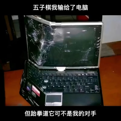 图片展示了一台严重损坏的笔记本电脑，屏幕布满蛛网状裂纹，机身似乎也有弯曲变形。图片上方配有文字“五子棋我输给了电脑”，下方配有文字“但跆拳道它可不是我的对手”。这张图通过幽默的方式表达了一个人在五子棋游戏中输给电脑后，可能因愤怒而用跆拳道的方式“报复”了电脑，导致电脑损坏。