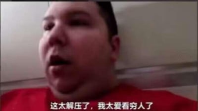 这是一张视频截图，画面里是一位穿着红色上衣的肥胖男子，他嘴巴微张，表情夸张，图片下方配有白色字幕“这太解压了，我太爱看穷人了”。这句话传递出一种扭曲、讽刺的价值观，以夸张的表述制造强烈反差，常被用作网络梗图，用来调侃或反讽那些以他人困境为乐的不良心态。