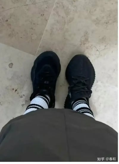 这张图拍摄的是一个人穿着两只不同款但都是黑色的运动鞋（左脚和右脚鞋款不同），黑白条纹袜子十分显眼。从俯拍视角看去，给人一种穿错鞋、急匆匆出门发现没对鞋的感觉。整体氛围轻松搞笑，存在明显的生活日常幽默和社死感梗。鞋子的颜色相近但款式不同，更增加“将就一下”或“糊里糊涂”的双关意味。该类型图片经常用来表达“状态不佳”、“粗心大意”、“搭配随意”等网络调侃情绪。

图片无明显谐音梗或暗示梗，但可类比“穿错鞋出门”梗，是都市生活中的自嘲搞笑瞬间。