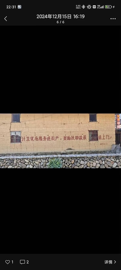 一张手机屏幕截图，显示了一面农村土墙上的红色标语，内容为'计生优质服务进农户，奖励扶助政策送上门'。截图显示拍摄时间为2024年12月15日，下方有点赞和评论按钮。