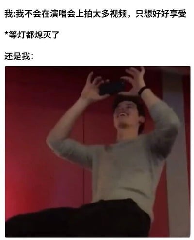 这张梗图通过文字与图片的强烈对比，生动展现了演唱会观众的经典矛盾心理。上方文字分为三部分：第一行写着“我:我不会在演会上拍太多视频，只想好好享受”（原文“演会”应为“演唱会”的笔误），第二行以“*等灯都熄灭了”作为转折提示，第三行“还是我:”引出下方实拍图。图片中是一名穿着浅色长袖上衣的男子，双手高高举起手机对准上方，身体微微后仰，脸上洋溢着兴奋的笑容，背景为红色墙面，完美还原了演唱会灯光熄灭后观众忍不住记录瞬间的场景。文字中“说不拍”与图片“疯狂拍”形成鲜明反差，精准戳中“真香定律”，展现了人们面对现场氛围时的真实反应。