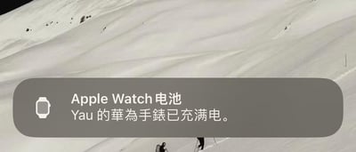 这张图片的背景是一片雪地户外场景，前景显示了一个苹果设备的系统通知栏。通知栏左侧带有Apple Watch的图标，通知标题标注为“Apple Watch电池”，但下方的具体提示文字却是“Yau的华为手表已充满电”，出现了品牌标识与通知内容完全不匹配的乌龙情况。这种系统识别或通知分类的错误，形成了强烈的反差感，制造出搞笑的效果，体现了跨品牌智能设备搭配使用时可能出现的系统bug。