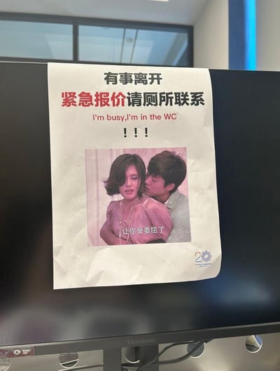 这张图片是一张贴在办公区显示器上的趣味告示，内容是提醒同事自己临时离开，有紧急情况可以去厕所找。上方采用了醒目的字体强调“紧急报价请厕所联系”，下方配上了一张带有“让你受委屈了”字幕的影视剧照作为趣味点缀，整体氛围轻松幽默，充满职场自嘲意味。

双关与暗示：文字里的“报价”谐音“抱价”，结合如厕场景，令人会心一笑。表达了职场人在被无休止打扰时的无奈和调侃。