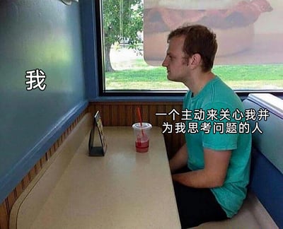 这是一张文字加注类静态梗图，画面场景为餐厅的卡座区域：一名身着蓝绿色短袖的男子独自坐在座位上，他的神情落寞，目光望向窗外，桌上摆放着一杯喝了一部分的红色带吸管饮品，对面的卡座座位空无一人。图中通过文字标注，将男子标注为“我”，对面的空座位标注为“一个主动来关心我并为我思考问题的人”，以此来具象化地表达出当下自己处于孤独状态，内心十分渴望能有主动关怀自己、为自己分忧解难的人出现的情绪，容易引发同样渴望被理解、被关怀的人群的共鸣。