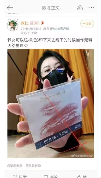 这是微博用户「咪比」发布的动态，发布于2024年5月26日天津。图中用户戴着眼镜和黑色口罩，手持一张印有唇印的透明卡片，配文表示梦女群体可以将唇印印制成这样的无料，在线下活动时送给男偶像。其中「β」是「唇」的谐音，「男癌豆」是对男偶像的调侃式称呼，属于粉丝圈梦女文化的创意应援内容。