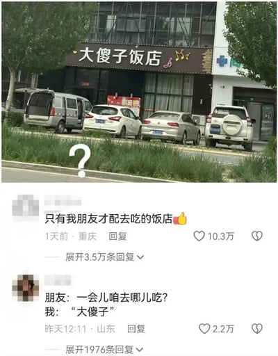 这张图片分为上下两部分，上半部分是现实拍摄的场景：一家名为“大傻子饭店”的线下店铺，店铺外观为深色招牌配黄色字体，还带有音符装饰，店门口的路边停放着四辆汽车，画面左侧有一个白色的问号，似乎在表达对这个店名的疑惑或调侃。下半部分是社交媒体平台的评论区截图，第一条高赞评论内容为“只有我朋友才配去吃的饭店👍”，获得10.3万点赞，发布地为重庆，发布时间为1天前，这条评论用饭店名字玩梗，调侃朋友是“大傻子”，是朋友间的玩笑式调侃；第二条是一段模拟对话，朋友问“一会儿咱去哪儿吃？”，回复是“‘大傻子’”，将饭店名作为目的地，制造出趣味效果，这条评论获得2.2万点赞，发布地为山东，发布时间为昨天12:11。整体内容围绕“大傻子饭店”这个充满趣味的店名展开，通过网友的评论玩梗，制造出轻松搞笑的效果。