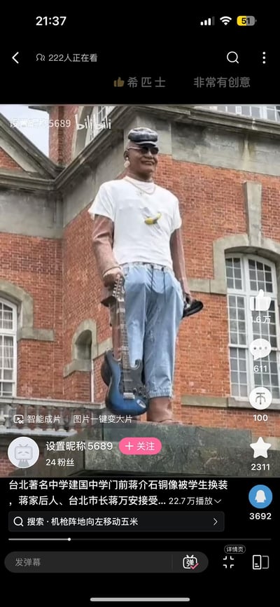 台北建国中学门前的蒋介石铜像被学生恶搞换装，原本严肃的历史人物雕像被换上了潮流休闲装：白色T恤、蓝色牛仔裤、黑色棒球帽，还戴着墨镜和金项链，手持电吉他摆出酷帅姿势，与身后的红砖古典建筑形成强烈反差。视频截图显示有222人正在观看，点赞数达1.6万，评论611条，网友评论"非常有创意"。