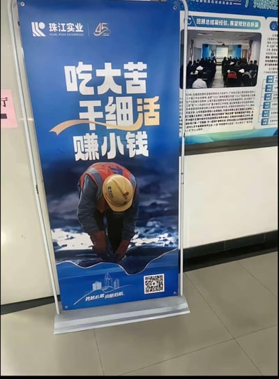 这是珠江实业的企业宣传易拉宝，整体为竖版图文混排样式，背景以深蓝色为主。顶部印有“珠江实业 PEARL RIVER ENTERPRISES”的企业标识和代表45周年的数字标识，核心位置用醒目白色字体呈现标语“吃大苦 干细活 赚小钱”，下方是一张实拍图：一位戴着黄色安全帽、身穿工装和反光背心的一线工人俯身专注作业，底部配有“跨越45载 向新启航”的文字和二维码。海报整体传递出务实肯干、踏实经营的企业作风，无谐音梗或双关含义。