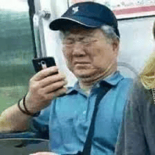 图片里是一位穿蓝色帽子和蓝色Polo衫的大叔坐在地铁座位上，手里拿着手机专注地看手机屏幕。左手腕上戴着黑色手环，身边还有另外一位女性乘客。整体场景是在地铁车厢内，反映了现代人日常通勤时的真实状态，手机成为生活必需品。

该图片常被用来表达“叔叔也沉迷手机”、“通勤日常”、“低头族”的相关话题，有时还会配上调侃式字幕。