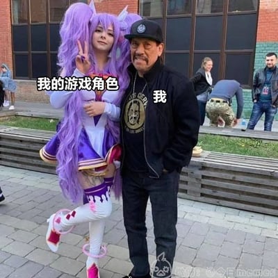 这是一张网络反差玩梗图，图中左侧是一位扮演可爱二次元女游戏角色的coser，被文字标注为“我的游戏角色”，右侧是知名硬汉男演员丹尼·特乔，被标注为“我”，玩的梗是多数男玩家玩网络游戏时偏好选择女性游戏角色，而本人实际是壮汉的反差笑点，图片拍摄于户外漫展类活动场地，背景还有其他路人。