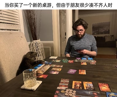 这张图片呈现了一个充满趣味的室内生活场景：一位戴眼镜的男士坐在摆满桌游卡牌、道具的深色桌子前，手中拿着手机，神情带着些许无奈。由于买了新桌游却凑不齐朋友一起游玩，他只能让自家的猫咪来充当“桌游伙伴”。猫咪趴在旁边的椅子上，一只爪子搭在桌上的卡牌上，姿态仿佛真的在认真参与游戏。桌上还放着一杯喝了一部分的饮品，整个画面既生动又带着独居爱好者的小窘迫，精准戳中了那些朋友较少、想玩桌游却无人组队的人的心境，充满了生活的趣味感。