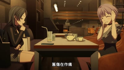 动画《MyGO!》中的咖啡厅场景，画面中有两位少女相对而坐。左侧少女留着黑色长发，身着黑色上衣，手托下巴静坐，眼神低垂似在沉思；右侧少女有着浅紫色短发，双手抱头，脸颊微红，双眼紧闭，表情透露出痛苦或困扰。桌上摆放着装有饮料的玻璃杯（带吸管）、茶壶、茶杯及一部手机，背景为暖色调灯光的室内环境，可见楼梯和座椅。画面底部有中文字幕“旧伤在作痛”。
