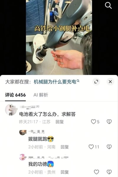 画面上半部分是在高铁车厢内拍摄的短视频：一只手正拿着充电线，为穿着白色运动鞋的机械假肢充电，字幕写着“高铁给小钢腿补点电”。“小钢腿”是对假肢的亲切称呼。下半部分是短视频平台评论区，顶部显示“大家都在搜：机械腿为什么要充电”，评论数为6456。第一条评论认真询问“电池着火了怎么办，求解答”，河南网友回复“拔腿就跑”。这个回复利用成语制造双关：“拔腿就跑”本来指立刻转身逃跑，在这里又可按字面理解为把机械假肢拔下来再跑，既回应了电池起火的隐患，也形成冷幽默。贵州网友评论“我的功德”并配大笑表情，表达自己被这种略带幸灾乐祸的梗逗乐。现实中如果假肢电池出现冒烟、异味、发烫或起火，不应按段子处理，应在确保安全的前提下停止使用并断开电源，立即告知高铁乘务员、远离电池，由工作人员使用合适设备处置，必要时配合疏散。
