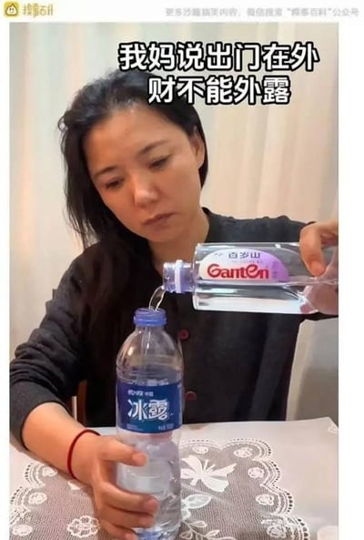 这是一张搞笑趣味梗图，图中一名女子故意将定价更高的百岁山矿泉水倒入定价更便宜的冰露矿泉水瓶中，配合上方配文“我妈说出门在外财不能外露”，用将“贵的水”藏在便宜水瓶里的行为，玩梗调侃“财不外露”的说法，通过反差制造出幽默感。