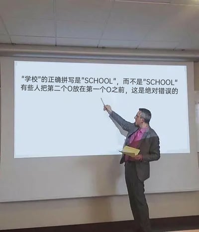 这是一张无厘头风格的搞笑梗图，画面呈现的是一个教学场景：一位穿着深色西装、内搭玫粉色衬衫的男性讲师，手持教鞭指向身后的投影屏幕，另一只手拿着黄色文件夹，神情严肃地进行内容讲解。投影屏幕上的文字声称“学校”的正确拼写是“SCHOOL”，而不是“SCHOOL”，还一本正经地指出“有些人把第二个O放在第一个O之前，这是绝对错误的”，但实际上“SCHOOL”里的两个O是完全相同的字符，无论调整这两个O的顺序，最终的拼写都不会有任何变化，这段所谓的拼写纠错完全是毫无意义的废话，通过讲师严肃认真的态度与荒诞无意义的内容形成强烈反差，制造出搞笑的效果。