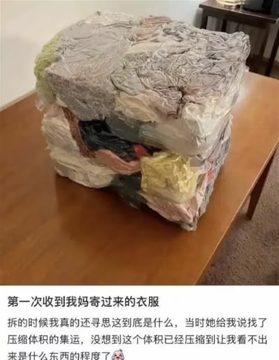这张图展示了一堆被极度压缩的包裹，堆放在木质桌面上，这些是博主妈妈通过压缩集运寄来的衣服，但压缩程度极高，完全看不出原本衣物的形态，像一块坚硬的方块。图下配文讲述了博主收到包裹时的疑惑心情，真实又搞笑地呈现了集运压缩“过度”的效果，很容易让有过类似集运经历的人产生共鸣。博主还玩了Minecraft的梗，将压缩后的衣服比作游戏里的方块，增添了趣味性。