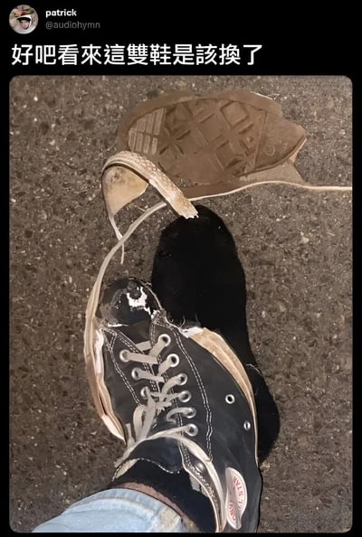 一张展示极度磨损的黑色运动鞋的照片，鞋底已完全脱落，鞋带磨损严重。图片上方有文字'好吧看來這雙鞋是該換了'，表达了鞋子需要更换的无奈情绪。