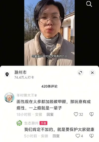 这是一张社交媒体内容截图，上半部分是一位佩戴眼镜、身穿浅卡其色羽绒服的女士在户外民居前拍摄的视频画面，画面配文为“尽量减少现代化化学物质的介入”，页面显示定位为安徽滁州市，共有74.4万人打卡。下方评论区有网友“羊村懒大王”玩化学梗，称“面包现在大多都加脱碳甲醛，那玩意有成瘾性，一上瘾就是一辈子”，其中“脱碳甲醛”是水（H₂O）的戏称，属于网友故意编造的唬人说法，而认证为作者的官方账号“生态滁州”没有识破该梗，回复称“我们肯定不加的，就是要保护大家健康”，这段错位回复形成搞笑效果。