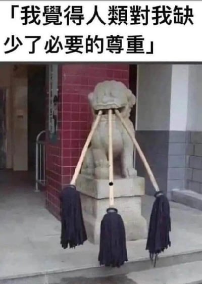 图片中展示了一尊位于建筑物入口处的石狮子雕像，其口中被插入了三把扫帚。雕像后方是红色砖墙和灰色建筑墙面。图片顶部配有文字：“我觉得人类对我缺少了必要的尊重”，通过拟人化的手法，将石狮子塑造成一个抱怨人类不尊重它的形象，用扫帚插入嘴中的滑稽场景与文字形成幽默对比，引发笑点。