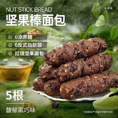 这是一张坚果棒面包的广告图片，面包被堆叠在白色盘子里，呈现出浓烈的黑巧味和坚果颗粒感。图片突出其健康属性，包括0添加蔗糖、0反式脂肪酸，并标有“扛饿坚果面包”。不过，因为面包的形状、颜色及排列方式，非常容易让人联想到类似生理意义上的梗图（如便便梗），在网络上经常被玩梗调侃。没有明显的双关词，但视觉暗示性极强。