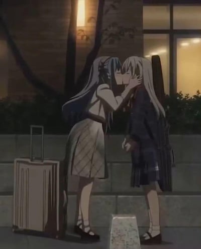 夜晚的户外街道旁，蓝发的原村和身着校服，身旁立着拉杆行李箱，正伸手抚着浅金发的宫永咲的脸颊，二人亲吻道别；宫永咲脚边放着一个包装好的物品，整体氛围带着离别的温柔与不舍，是百合向动画中的经典场景。