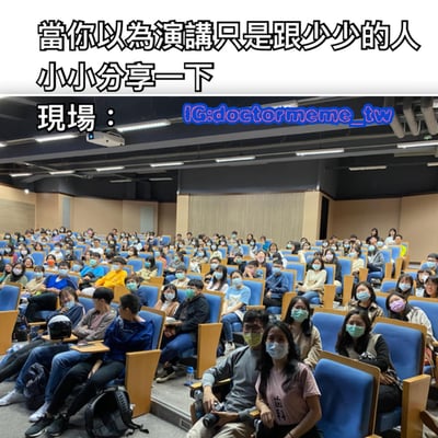 图片上方配有文字“當你以為演講只是跟少少的人小小分享一下 現場：”，下方是一张大型阶梯教室的照片，里面坐满了戴着口罩的观众，蓝色座椅几乎全部被占据，形成了预期中“小小分享”与实际“大型现场”的鲜明对比，带有搞笑和意外的效果。