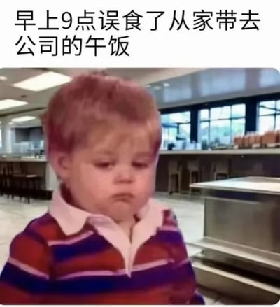 这是一张面向上班族的趣味梗图，采用顶配底文的图文混排形式，顶部配文为“早上9点误食了从家带去公司的午饭”，下方搭配面露委屈郁闷的外国小男孩表情包，背景是类似食堂的餐饮场所。配文表面称自己是误食午饭，结合标题“并非误食”实际是调侃打工人早上过于饥饿，忍不住提前吃掉了准备中午吃的带饭，吃完后又发愁中午没饭吃的懊恼无奈的状态，用小男孩的委屈神态精准贴合了这种矛盾又好笑的心情。