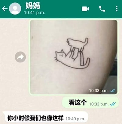 这是一张微信聊天记录截图，显示与妈妈的对话。妈妈发送了一张纹身照片，纹身图案是两只猫咪玩耍，一只猫正抓住另一只猫的爪子。随后妈妈留言："你小时候我们也像这样"，用猫咪互动的可爱画面比喻童年时期的亲子关系，充满温馨怀旧感。