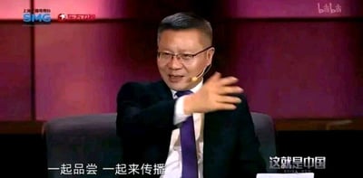 这是东方卫视政论节目《这就是中国》的录制截图，画面中的主讲人张维为身着黑色西装、白色衬衫搭配紫色领带，佩戴眼镜与耳挂式麦克风，正伸出一只手，神情投入地进行发言。画面底部配有字幕“一起品尝 一起来传播”，左上角显示上海广播电视台SMG与东方卫视的标识，右上角有bilibili平台水印，右下角标注节目名称“这就是中国”，整体场景为正式的节目演播室，传递出观点传播的氛围。