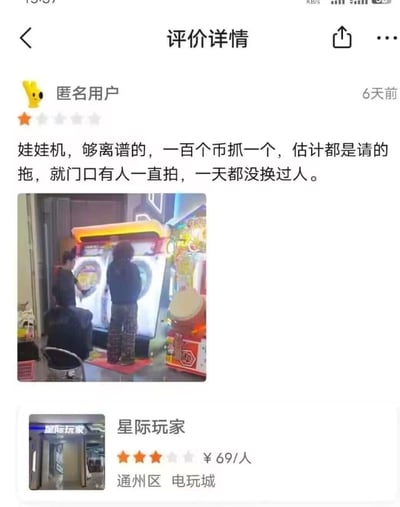 这是一张手机截图，内容为某电玩城的用户评价详情页。匿名用户给出1星差评，吐槽娃娃机“一百个币抓一个”，并怀疑商家请托，称“门口有人一直拍，一天都没换过人”。配图显示两名顾客正在操作娃娃机，背景可见电玩城内的其他游戏机。页面底部显示商家信息：“星际玩家”电玩城（通州区），人均消费69元，评分为3星。