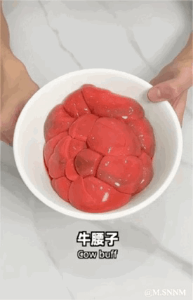 图中一双手捧着一个白色的碗，碗内盛放着多块新鲜的红色牛腰子，食材色泽鲜亮。画面下方配有文字标注“牛腰子 Cow buff”，明确食材名称，但其中英文标注存在错误，牛腰子的正确英文应为“Cow kidney”。