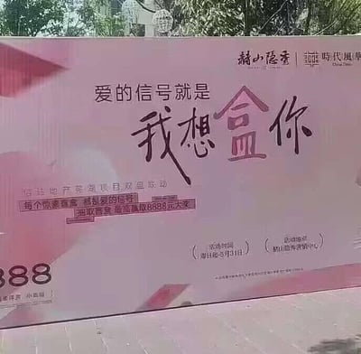 图片展示了一块房地产项目的户外广告牌，背景为粉色渐变，整体设计偏向浪漫风格。广告牌中央以醒目字体写着核心标语“爱的信号就是 我想盒你”，其中“盒你”巧妙运用谐音梗，与“和你”发音相近，营造出俏皮的爱情信号主题。左上角和右上角分别标注了项目名称“赭山隐秀”与“新时代·凤凰”，下方详细说明为“信达地产芜湖项目双盘联动”，并强调“每个点赞都是爱的信号”，同时宣传抽取至高8888元大奖的活动。底部标注了活动时间（4月14日-5月31日）和地点（赭山隐秀营销中心）。画面背景可见树木，推测广告牌位于户外公共场所。