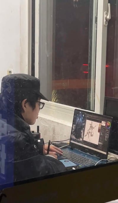 这是一张透过玻璃窗拍摄的照片，雪夜中，一位戴着帽子和眼镜、穿着厚外套的创作者正坐在窗边，在笔记本电脑上进行数字绘画创作。电脑屏幕上能看到正在绘制的人物线稿和一张风格化的参考图，窗外的玻璃上落着雪花，整个场景安静又充满专注感，展现了绘画从业者投入工作的日常瞬间。