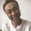 图片中是一位穿着白色衬衫的中年男性，他面带微笑，表情看起来有些憨厚和开心。人物面向镜头，背景简单，没有明显的环境特征。