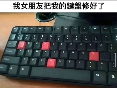 图片展示了一个黑色键盘，键盘上的A、D、W、S四个按键被替换成了醒目的红色按键。图片上方配有文字“我女朋友把我的键盘修好了”，暗示原本可能因长期使用（尤其是游戏中常用的WASD移动键）而磨损的按键被女朋友贴心更换，形成一种温馨又略带幽默的场景。