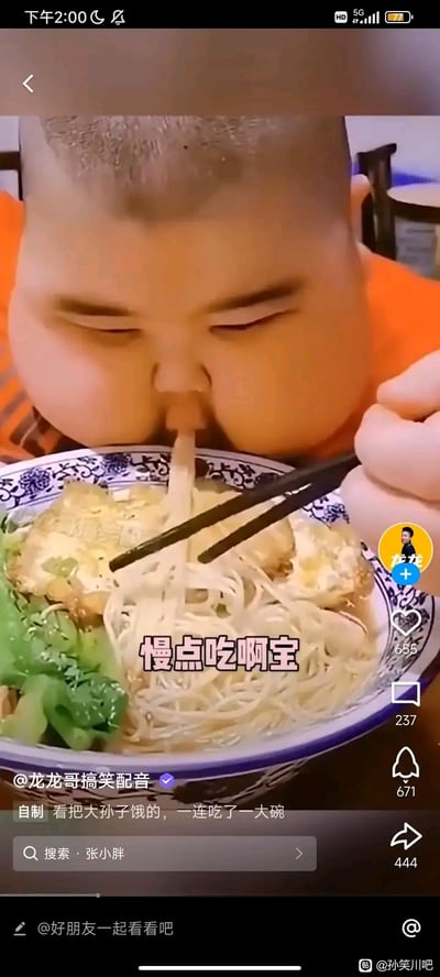 这是一段抖音搞笑配音视频的截图，画面里一个胖小孩正狼吞虎咽地吸溜一碗配有煎蛋和青菜的面条，画面中配文“慢点吃啊宝”，下方视频文案写着“看把大孙子饿的，一连吃了一大碗”，用长辈式的语气调侃小孩吃饭的急切模样，整体风格诙谐搞笑，充满生活趣味。