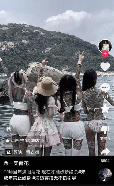 这是一张抖音平台的视频截图，画面主体是四位背对镜头站在海边浅滩的女孩：其中三位女孩有着大面积的通体纹身，穿着白色系的清凉海边穿搭，另一位女孩穿着粉白洛丽塔风格裙装、戴着草帽，几位女孩都举起手比出不同的手势，背景是覆盖绿植的山石与海面。截图下方显示了抖音的互动数据：点赞3461、评论381、收藏311、转发6994，还有发布者@一支荷花的文案：“军师当年满眼泪花 现在才能步步绝杀#未成年禁止纹身 #海边穿搭无不良引导”，同时标注了视频由剪映制作，配乐为“青衣dj”，界面还有“少推荐”“点击推荐给朋友”等按钮。文案特意强调了未成年禁止纹身，无不良引导，避免产生不良影响。