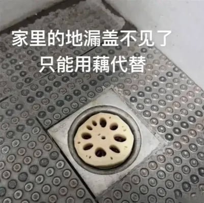 这张图展示了卫生间的防滑地砖区域，原本的地漏盖缺失后，有人将一片切好的莲藕片嵌在地漏的圆形凹槽中，莲藕本身自带的多枚孔洞刚好可以起到类似地漏盖排水的作用，图片上方配有白色文字说明，以荒诞又恰好适配的反差感制造笑点，整体充满无厘头的搞笑氛围。