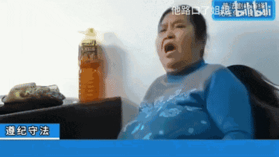 这是一段动态GIF表情包，画面中一位身着蓝色上衣的中老年女性做出极度夸张的惊讶表情，张大嘴巴，身体向后倚靠，呈现出强烈的震惊、错愕感。画面左下角有蓝色底白字的“遵纪守法”字幕，右上角带有“他路口了姐”的水印文字，该图常被网友用于社交聊天或评论中，表达遇到意外、离谱事件时的惊讶情绪。